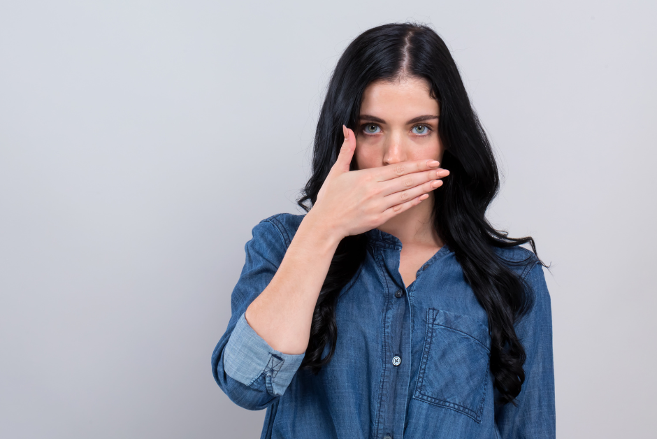 Woman suffering with angular cheilitis covering her mouth