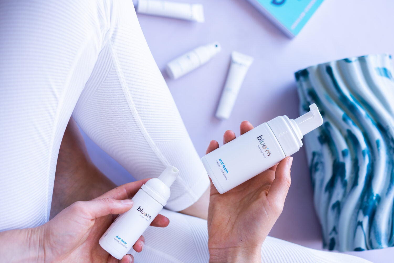 Lady on yoga mat holding bluem products