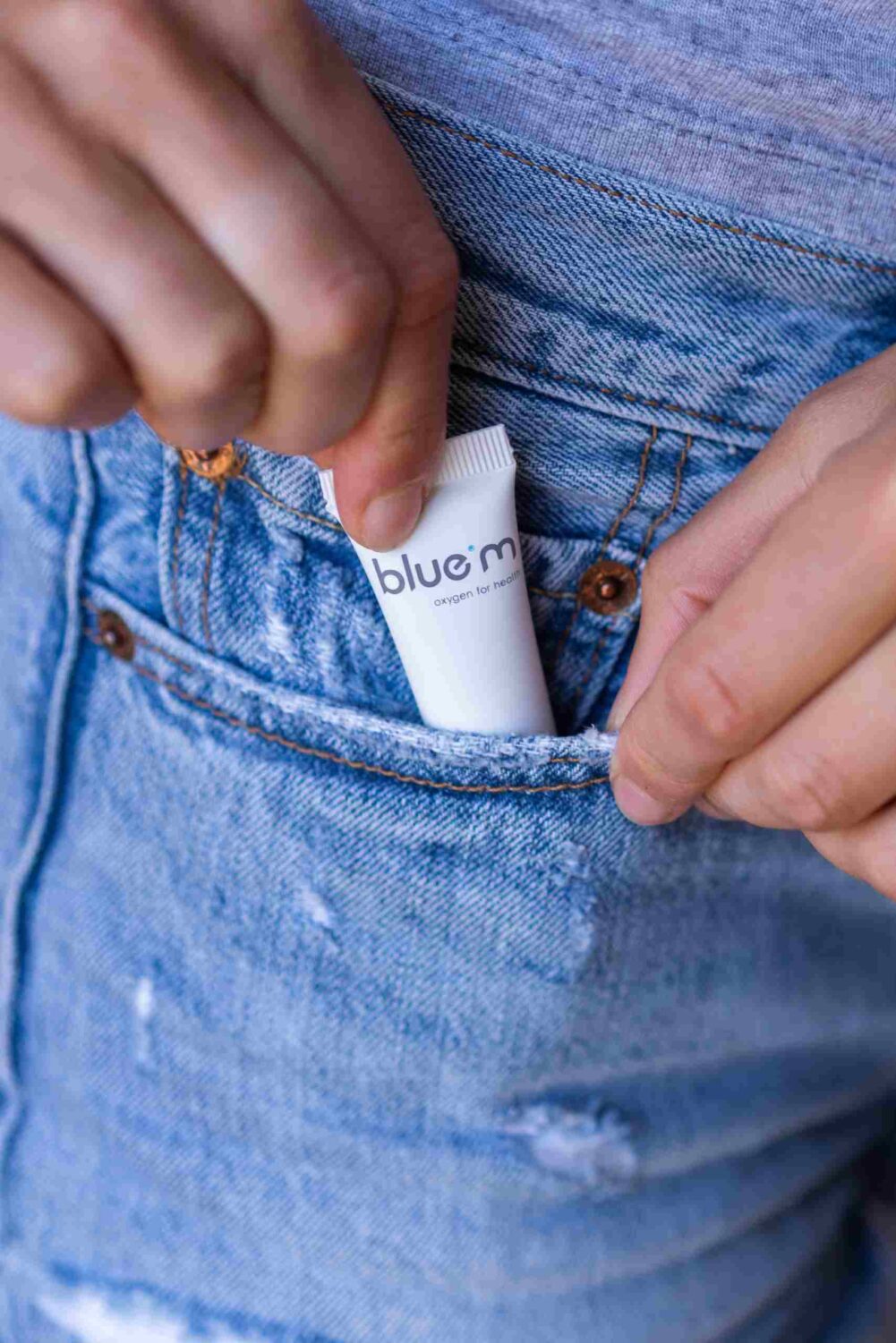 Woman with bluem oral gel in pocket to treat oral ulcers