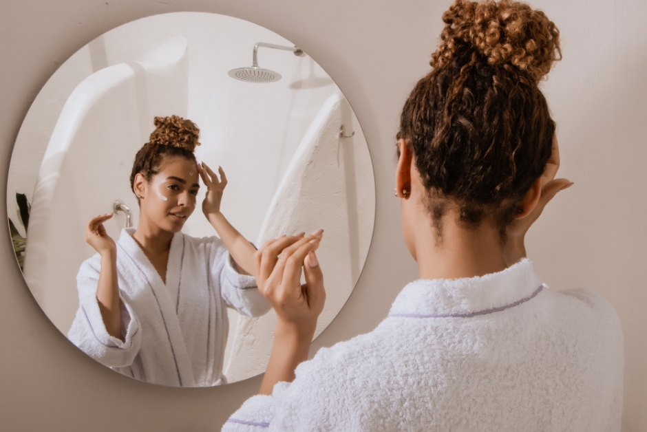 A woman doing her skin care in the mirror