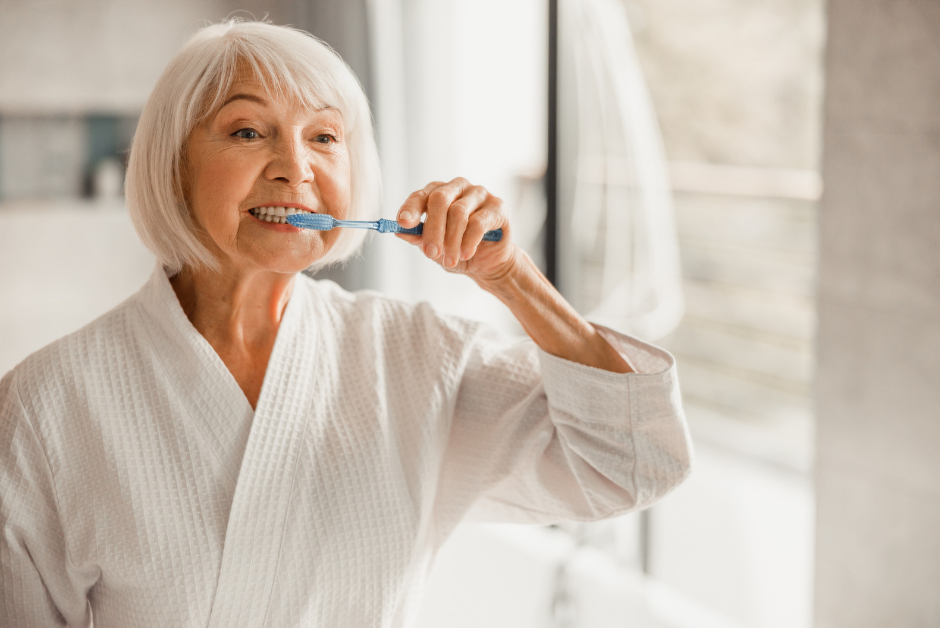 A older woman, brushing her teeth in the bathroom in a robe