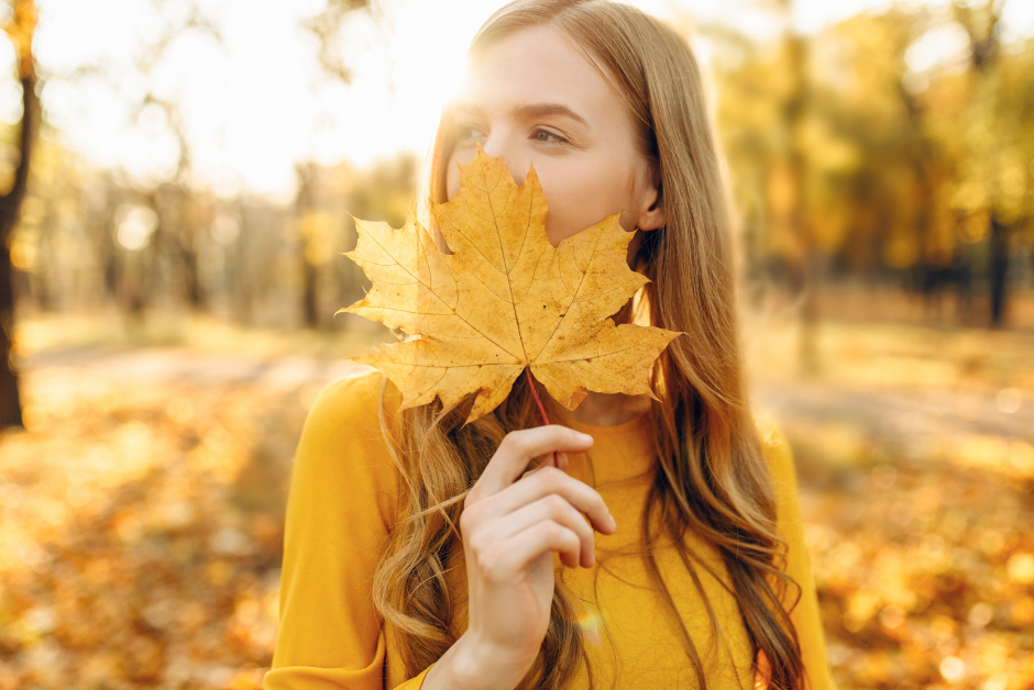 A woman in a forest holding a leaf in front of her mouth
