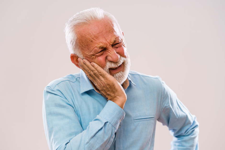Elderly man with peri-implantitis holding his face