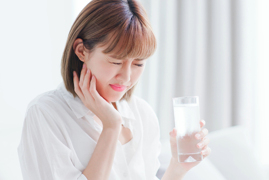 Lady with sensitive teeth holding a glass of water