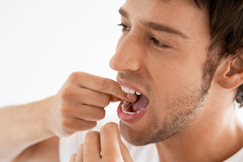 Man flossing teeth to avoid dental plaque