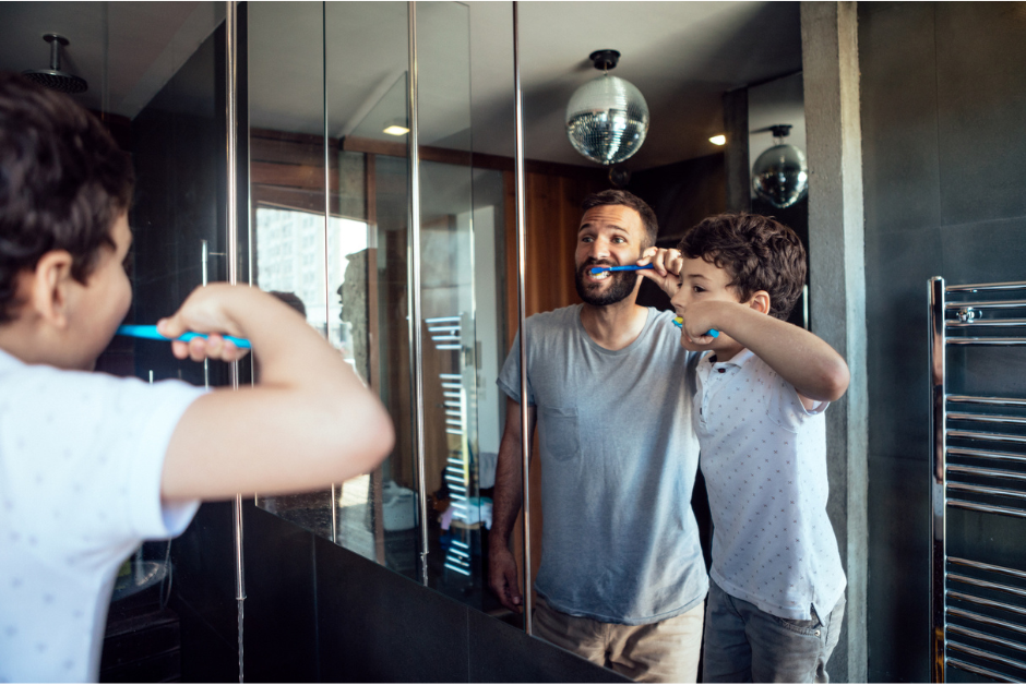 Father and son brushing their teeth, spotting the signs of dental plaque.