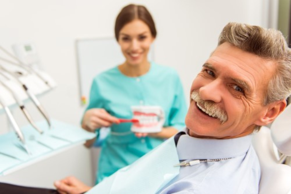 Man with dental implants smiling whilst sat in a dental chair